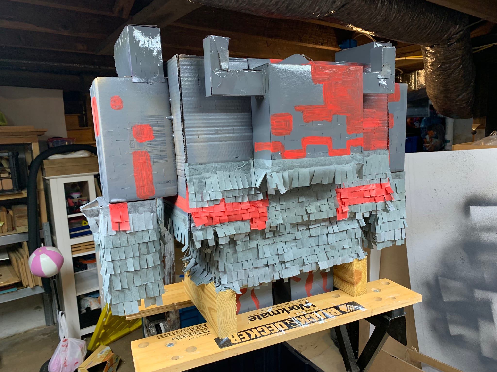 Adding tissue paper fringe to the piñata, starting from the bottom and working upward.